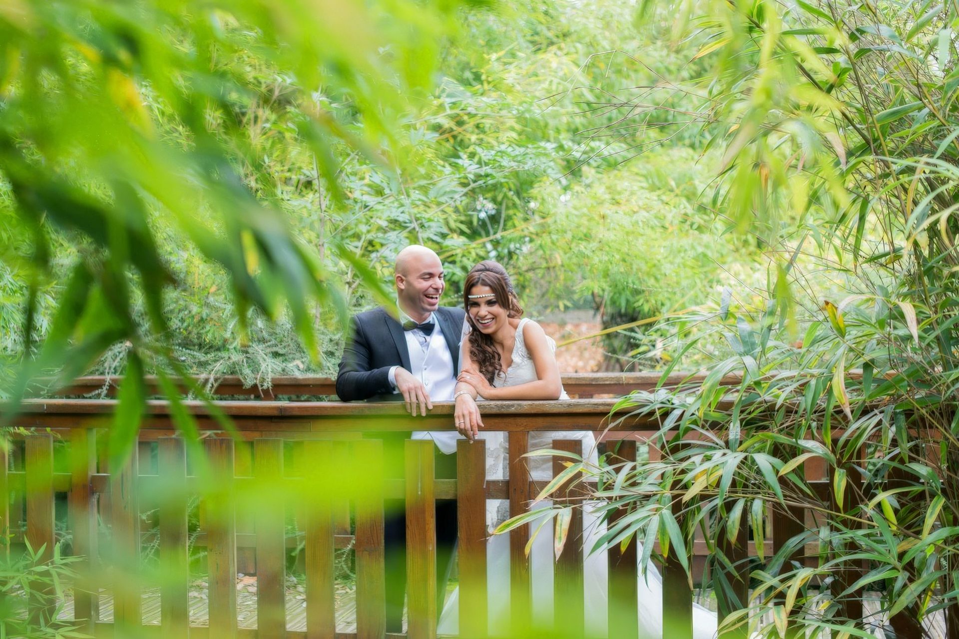 Mariés riant sur un pont en bois entouré de bambous – photographe mariage Paris