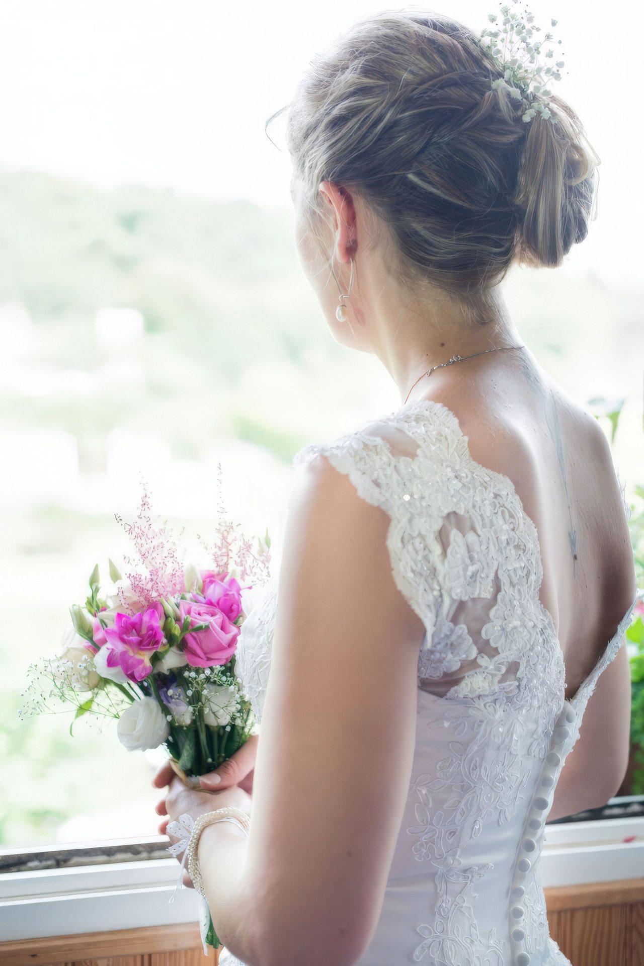 Mariée de dos à la fenêtre avec son bouquet – photographe mariage Créteil