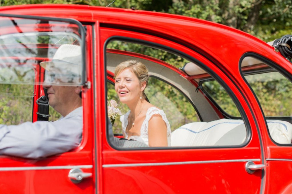 Mariée souriante à bord d'une 2CV rouge – photographe mariage Essonne
