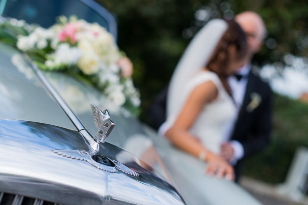 Mariés s'embrassant près d'une voiture de collection – vidéaste mariage Paris