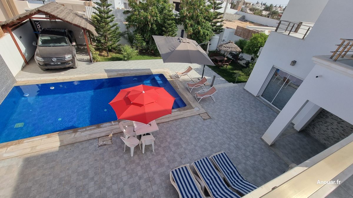 Terrasse, transats rayés et parasol rouge au bord de la piscine, vacances à Djerba