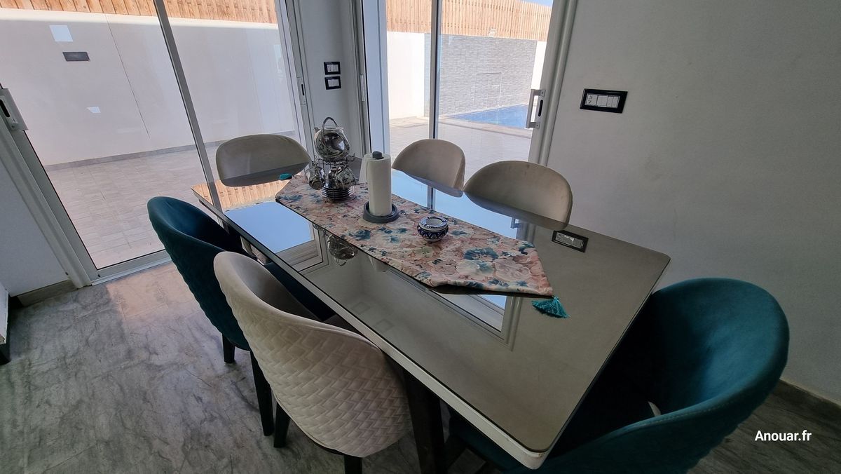 Table de salle à manger avec six chaises, baies vitrées sur la piscine