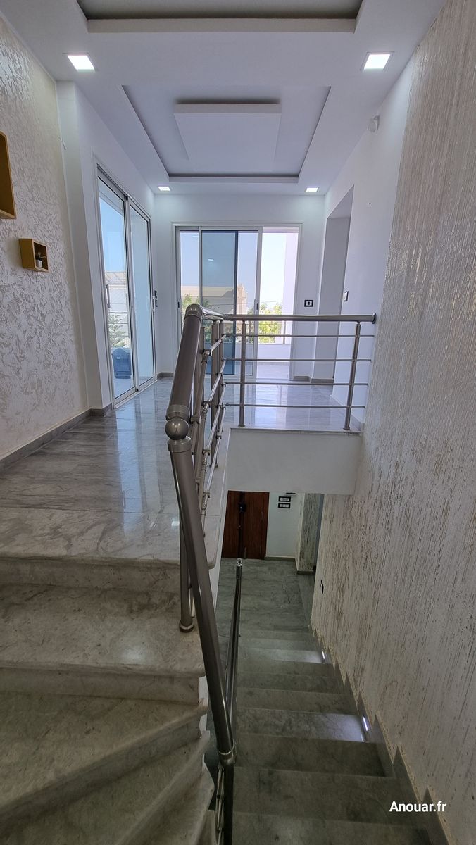 Étage lumineux de la villa avec baies vitrées et escalier en marbre