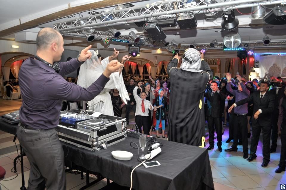 Mariée voilée et invités qui dansent avec le DJ pendant un mariage algérien