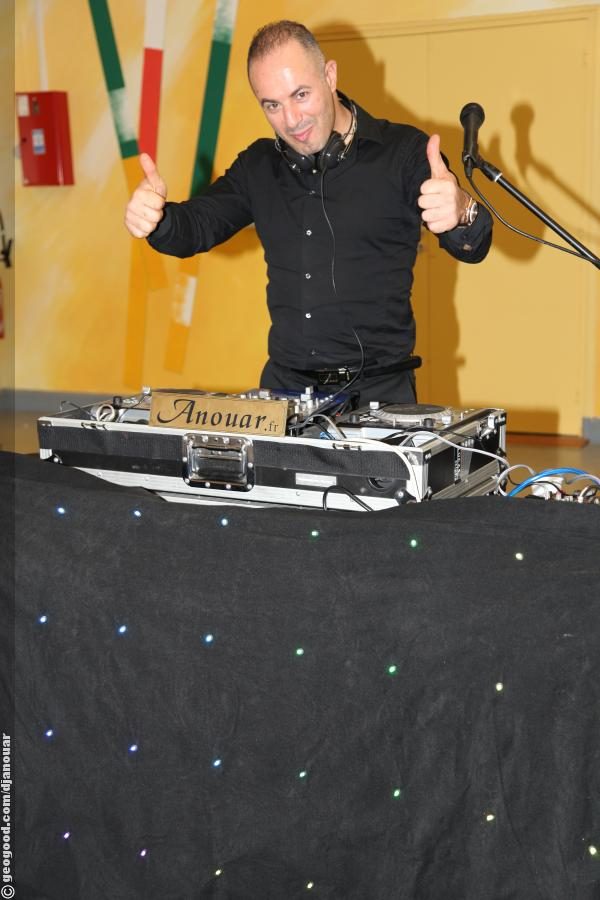 DJ pouce levé derrière ses platines pendant un anniversaire en salle à Évry